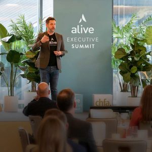A photo from the alive Executive Summit on a beige background.
