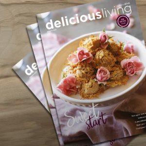 delicious living health and wellness magazine on wooden surface.